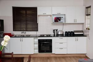 a kitchen with white cabinets and a stove top oven at Crystal Apartments in Lilongwe