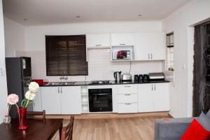 a kitchen with white cabinets and a table with flowers at Crystal Apartments in Lilongwe