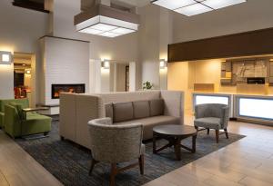 a lobby with a couch and chairs and a fireplace at Holiday Inn Express Hotel & Suites Belmont, an IHG Hotel in Belmont