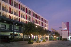 a large building with palm trees in front of it at Eco Inn Lite Ubon Ratchathani in Ubon Ratchathani