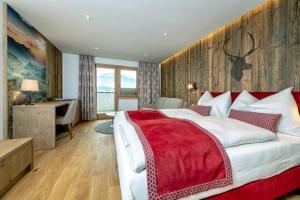 a bedroom with a large bed with a red blanket at Hotel Schörhof in Saalfelden am Steinernen Meer