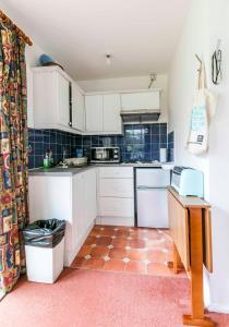 a kitchen with white cabinets and a tile floor at Pass the Keys Cosy & Bright Studio with Garden View Free Parking in Cambridge