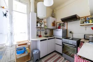 a small kitchen with white cabinets and a stove at GuestReady - Beautiful Apt - 5 mins to Chinatown in Paris