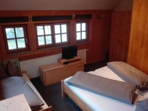 a room with two beds and a tv and windows at Ferienwohnung Holzer in Sankt Michael im Lungau