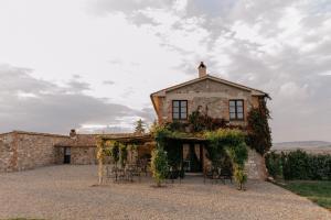 an old stone building with chairs and vines on it at Locanda in Tuscany in Castiglione dʼOrcia