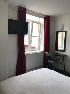 a bedroom with a bed and a desk and a window at Hotel La Basilique in Épinal