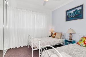 1 dormitorio blanco con 1 cama, mesa y sillas en Studio 11 Mandurah Marina, en Mandurah