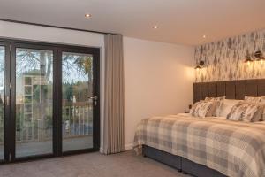 a bedroom with a bed and a sliding glass door at Thatched Eaves in Ibsley