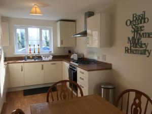 a kitchen with white cabinets and a table and a sink at New and Comfortable with Parking in Andover
