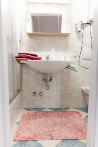 ein Badezimmer mit einem Waschbecken und einem rosa Teppich in der Unterkunft Wohnung am See in Steinbach am Attersee