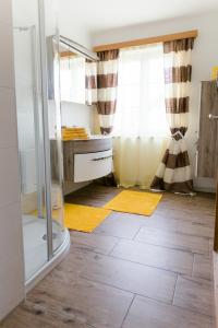 a bathroom with a shower and yellow rugs at Wohnung am See in Steinbach am Attersee