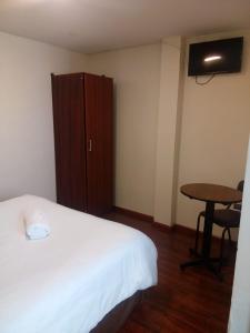 a bedroom with a bed and a table and a cabinet at Hotel Saint Thomas in Quito