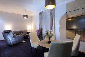 a living room with a couch and a table and chairs at Mercure Tetovo in Tetovo