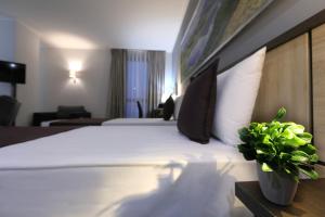 テトヴォにあるMercure Tetovoの白い大型ベッドと植物が備わるホテルルームです。