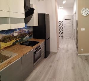 uma cozinha com armários brancos e piso em madeira em Apartament Przytulny Podolany em Poznań