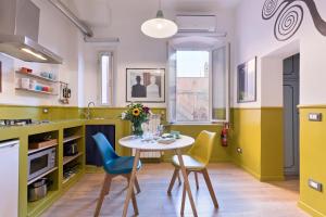 une cuisine avec des chaises jaunes et bleues et une table dans l'établissement Rome As You Feel - Orti Trastevere Apartment, à Rome