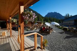 a wooden deck with picnic tables and an umbrella at Reitstall und Saloon San Jon in Scuol
