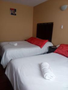 2 camas en una habitación de hotel con sábanas blancas y rojas en Hotel Saint Thomas, en Quito