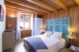 1 dormitorio con 1 cama con cabecero azul y ventana en Chalet Les Copains en Les Deux Alpes