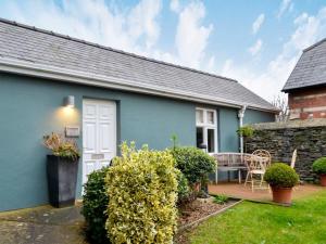 a blue house with a white door and a patio at Llys Celyn - Holly Farm in Aberystwyth