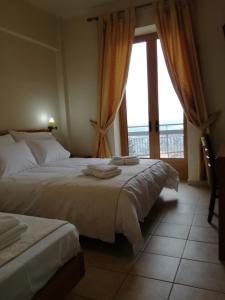 a bedroom with two beds and a large window at PARNON HOTEL in Áyios Pétros