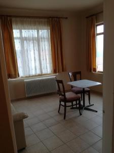 ein Wohnzimmer mit einem Tisch, Stühlen und Fenstern in der Unterkunft PARNON HOTEL in Áyios Pétros