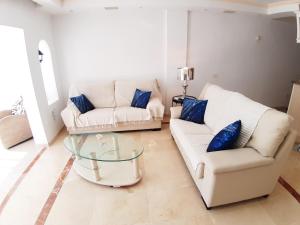 een woonkamer met twee witte banken en een glazen tafel bij LOS CRISTIANOS LUXURY SEA VIEW in Arona