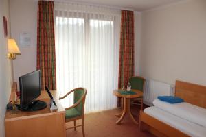 um quarto de hotel com uma cama e uma mesa com uma televisão em Villa Waldeck em Eppingen