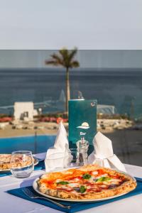 a table with a pizza on top of a table with a view of the ocean at Royal Palm Resort & Spa - Adults Only in Playa Jandia