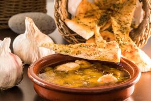 a bowl of soup with a piece of bread and garlic at Royal Palm Resort & Spa - Adults Only in Playa Jandia
