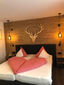 a bedroom with a bed with antlers on the wall at Pension Posthansl in Heiterwang