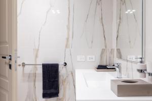 une salle de bain blanche avec un lavabo et un miroir dans l'établissement Palazzo Visconti - by MyHomeInComo, à Côme 36 autres photos