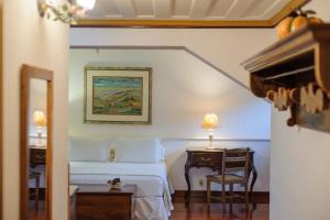 a bedroom with a bed and a desk with a chair at Pousada do Mondego in Ouro Preto