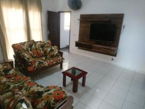 a living room with two couches and a flat screen tv at Fonseca's House in Itanhaém
