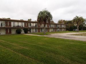 a large building with palm trees in front of it at Sunrise Inn Lake Charles in Lake Charles