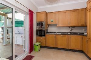 cocina con armarios de madera y cortina roja en Villa Amoreira by ALGARVEMANTA, en Manta Rota