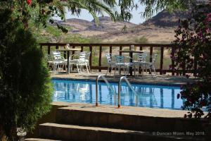 a pool with white chairs and tables and a table and chairs at Corona Guest Farm in Corona