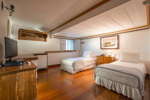 a hotel room with two beds and a television at Pousada do Mondego in Ouro Preto