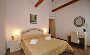 een slaapkamer met een bed, 2 tafels en een spiegel bij Ca' Alansari in Venetië