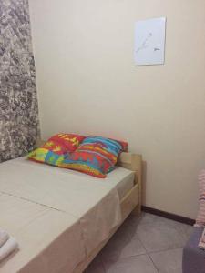 a bed with two colorful pillows in a room at Ap Palmarejo in Praia