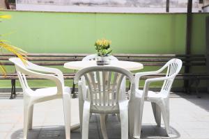 un tavolo bianco con tre sedie e un vaso di fiori sopra di Pousada Anexo a Niterói
