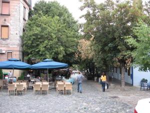 dos personas caminando por una calle con mesas y sombrillas azules en Belgrade Stay Apartments, en Belgrado
