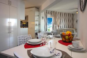 una cucina e una sala da pranzo con tavolo, piatti e bicchieri da vino di Vistamar a Rogoznica (Rogosnizza) Altre 28 foto
