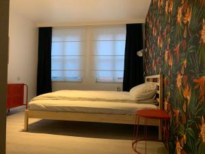 een slaapkamer met een bed en een raam met een muurschildering van bloemen bij Elma’s Place in Gent