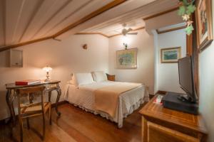 a bedroom with a bed and a table and a television at Pousada do Mondego in Ouro Preto +43 photos
