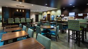 a restaurant with tables and chairs and a bar at Holiday Inn Express & Suites Midland South I-20 by IHG in Midland