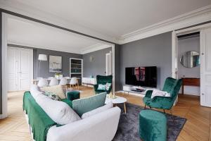 a living room with green and white furniture and a tv at Veeve - Emerald Exuberance in Paris