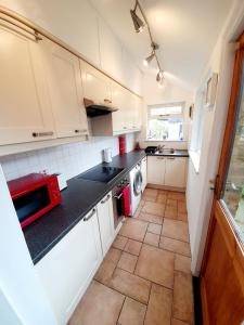 eine Küche mit weißen Schränken und einer roten Mikrowelle in der Unterkunft Chelmsford Centre House in Chelmsford