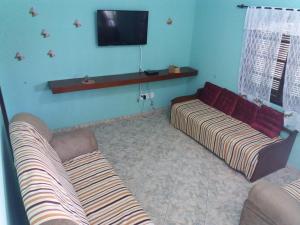 a living room with a couch and a flat screen tv at Casas Chateau do Bom Baiano in Cabo Frio