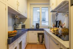een keuken met witte kasten en blauwe aanrechtbladen bij Veeve - Quai aux Fleurs Apartment in Parijs